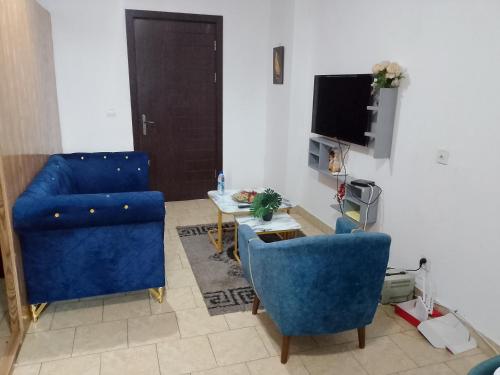 ポワントノワールにあるUn studio meublé mis en location journalièreの青い椅子2脚とテレビのあるリビングルーム
