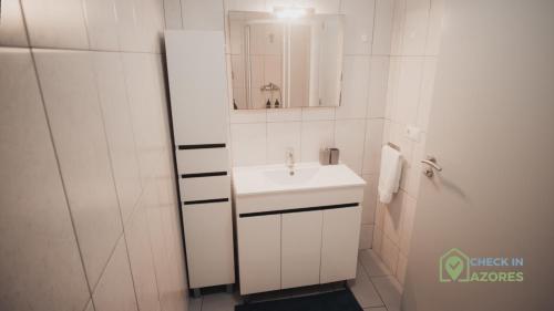 a white bathroom with a sink and a mirror at Apartamento acolhedor com AC no centro de Angra in Angra do Heroísmo