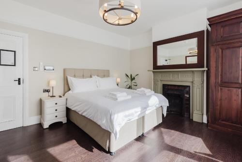 a white bedroom with a bed and a fireplace at Grace's Guesthouse Room 4 in Tring