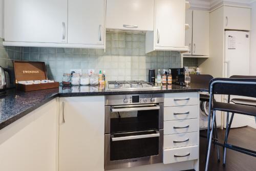 a kitchen with white cabinets and a stove top oven at Grace's Guesthouse Room 3 in Tring