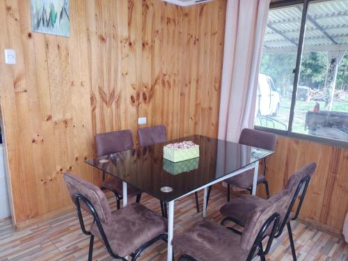 a dining room table with chairs and a cake on it at Cabaña Puipuyen Yerbas Buenas 