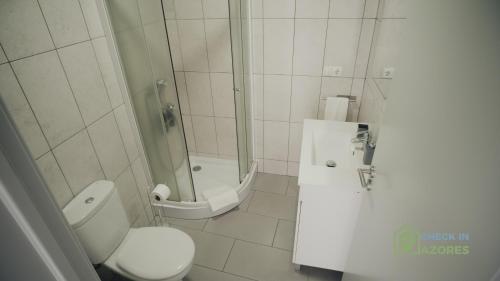 a bathroom with a toilet and a shower at Terraço e vista deslumbrante no centro de Angra in Angra do Heroísmo