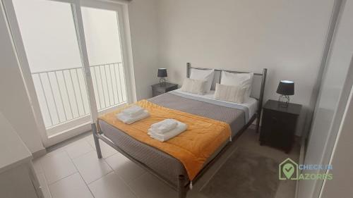 a bedroom with a bed with two towels on it at Terraço e vista deslumbrante no centro de Angra in Angra do Heroísmo