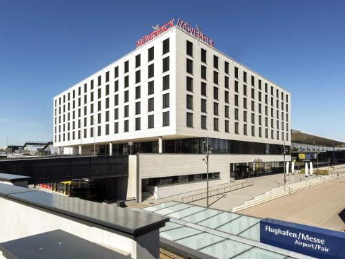 a large white building with a sign on top of it at Mövenpick Hotel Stuttgart Messe & Congress in Stuttgart
