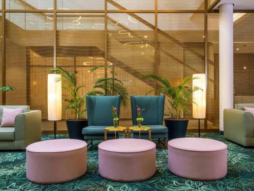 a lobby with chairs and tables and plants at Mövenpick Hotel Stuttgart Messe & Congress in Stuttgart