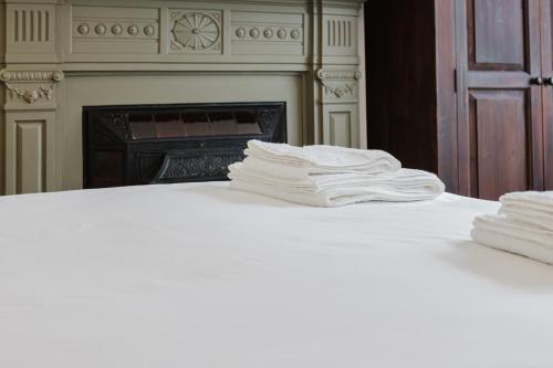 a stack of white towels on a bed with a fireplace at Grace's Guesthouse 68b in Tring