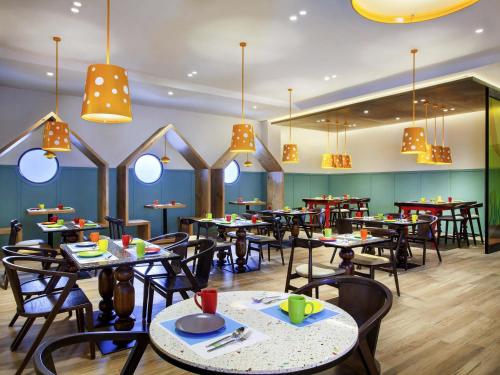 a restaurant with tables and chairs and chandeliers at ibis Styles Bandung Grand Central in Bandung