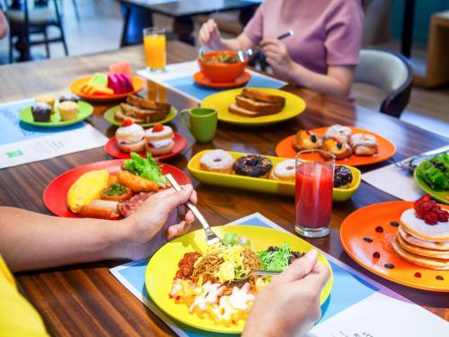 a group of people sitting at a table with plates of food at ibis Styles Bandung Grand Central in Bandung