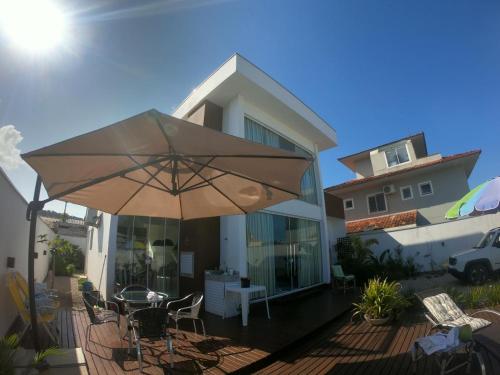 a patio with a table and an umbrella in front of a house at MarisC&LHouse2-Quarto para casal in Bombinhas