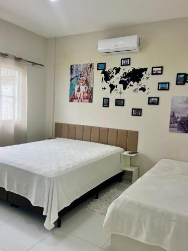 a bedroom with two beds and pictures on the wall at MarisC&LHouse2-Quarto para casal in Bombinhas
