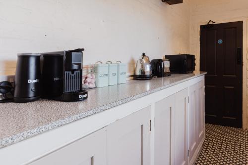 a kitchen counter with coffees and appliances on it at Grace's Guesthouse 68b in Tring