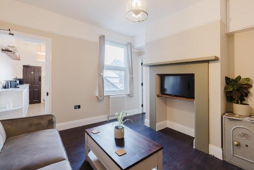 a living room with a couch and a tv at Grace's Guesthouse 68b in Tring
