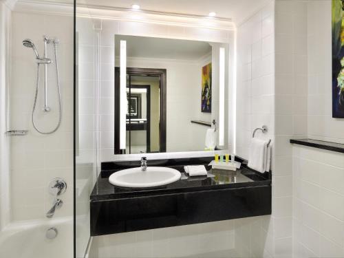 a bathroom with a sink and a shower and a mirror at Mövenpick Hotel Amman in Amman