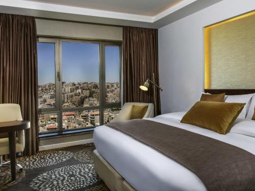 a hotel room with a bed and a large window at Mövenpick Hotel Amman in Amman