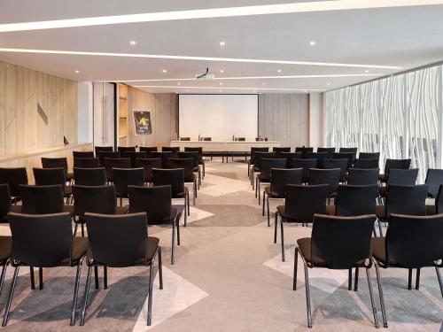 a conference room with chairs and a projection screen at Ibis Samarinda in Samarinda