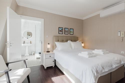 a white bedroom with a large bed and a chair at Grace's Guesthouse 68a in Tring