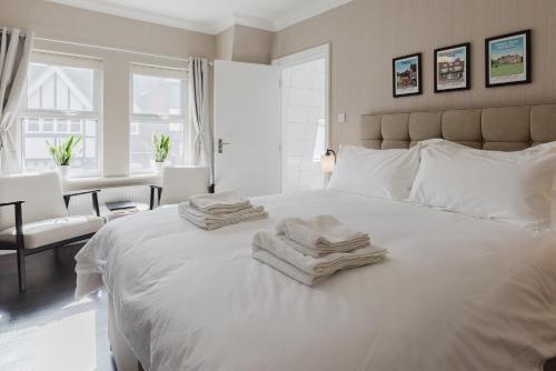 a bedroom with a white bed with towels on it at Grace's Guesthouse 68a in Tring