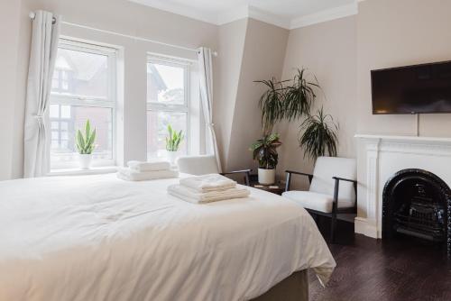 a white bedroom with a bed and a fireplace at Grace's Guesthouse 68a in Tring
