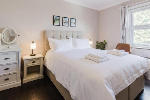 a bedroom with a white bed with towels on it at Grace's Guesthouse 68a in Tring