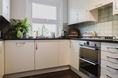 a kitchen with white cabinets and a window at Grace's Guesthouse 68a in Tring