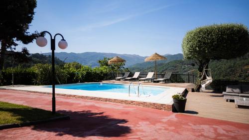 a swimming pool with chairs and umbrellas at Casa das Pedras in Vieira do Minho