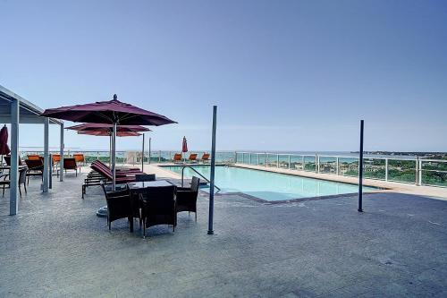 a pool with a table and chairs and an umbrella at Stylish Studio at Hotel Arya King Bed Full Kitchen City View Balcony and Parking in Miami