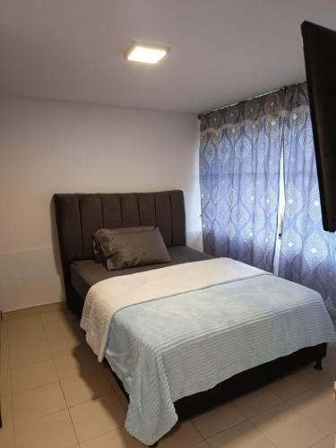a bedroom with a bed with a blue curtain at Excellent Studio Apartment in Zona Rosa Milan in Manizales