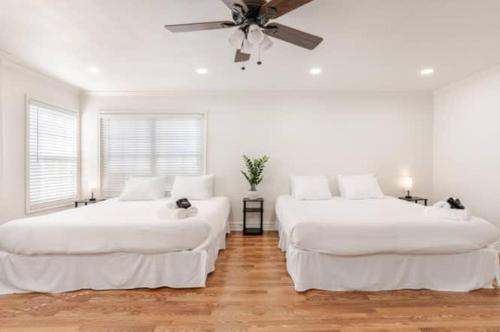 two beds in a white room with a ceiling fan at CA3 House Spacious SoCal Home for Groups in La Palma