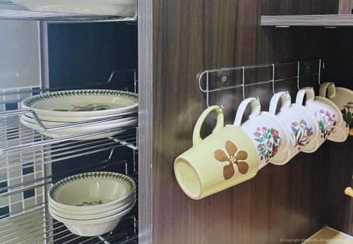 Un armario lleno de platos, tazas y vajilla. en Tamara Presint 8 Putrajaya Lakeview Suites, en Putrajaya