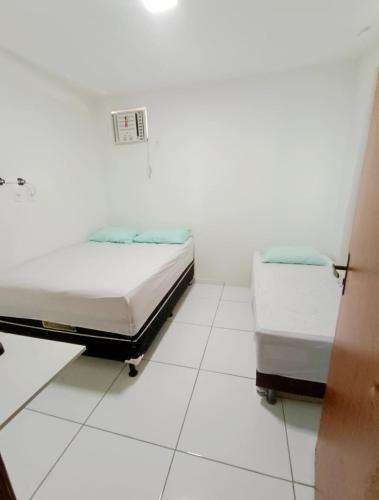 two beds in a room with white tile floors at Casa de Praia Frances in Marechal Deodoro