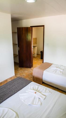 a hotel room with two beds and a door at Pousada Plenamar in Maragogi