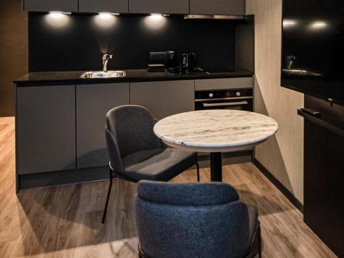 a kitchen with a table and a chair and a sink at Mercure Antwerp City South in Antwerp