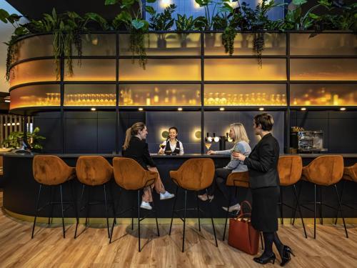 a group of people sitting at a bar in a restaurant at Mercure Antwerp City South in Antwerp