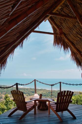 two chairs and a table on a deck with a view at Puerto Alto Hostel in Santa Marta