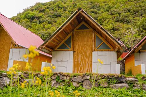 a wooden house with a mountain in the background at Yawar inka ayllu challhuay in Colcapampa