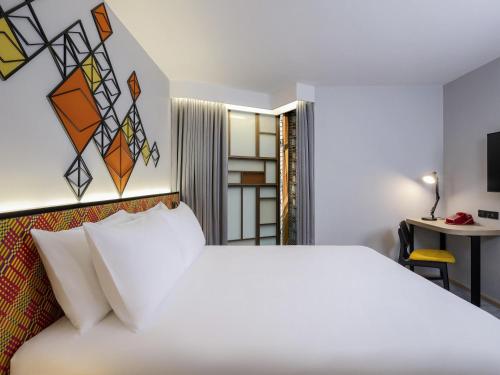 a bedroom with a white bed and a desk at ibis Styles Bangkok Silom in Bangkok