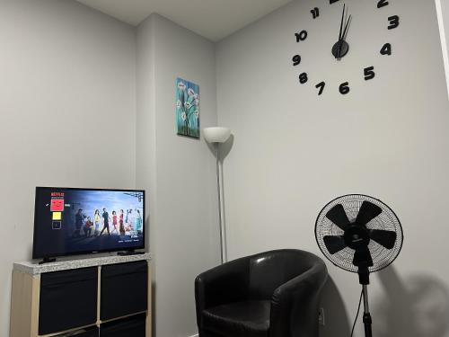 a room with a chair and a fan and a clock at 1-bedroom private suite, 20 minutes from the airport, with a kitchen in Edmonton
