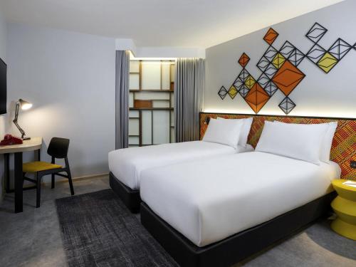 a hotel room with two beds and a desk at ibis Styles Bangkok Silom in Bangkok