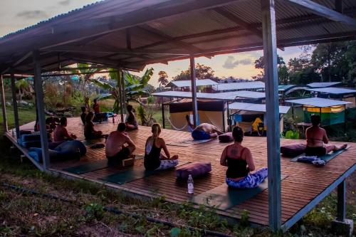 eine Gruppe von Leuten, die Yoga auf einer Holzterrasse machen in der Unterkunft Rainforest Glamping, Forest Bathing in the Osa Region in Ciudad Cortés