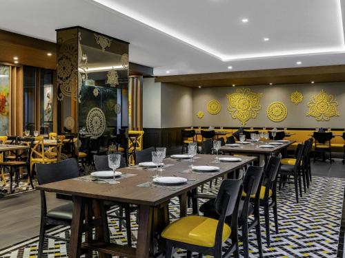 a dining room with wooden tables and chairs at ibis Styles Bangkok Silom in Bangkok