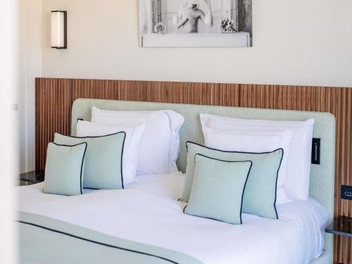 a bed with white sheets and blue pillows at Mondrian Cannes in Cannes