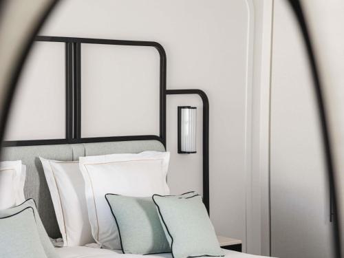 a bedroom with a bed with white pillows and a mirror at Mondrian Cannes in Cannes