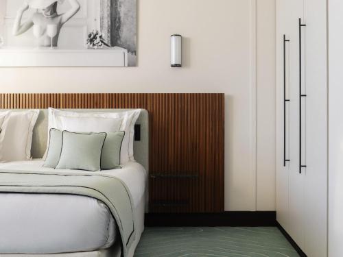 a bedroom with a white bed with a wooden headboard at Mondrian Cannes in Cannes