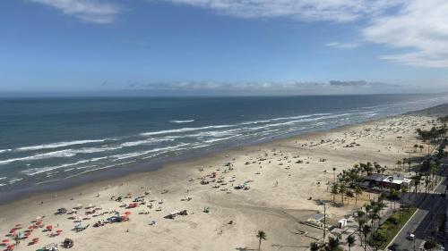 a beach with a lot of people and the ocean at Apartamento com Prédio Frente Mar in Praia Grande