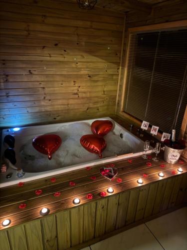 a wooden tub with three hearts in a room with lights at Pousada dos Canyons - chalé 01 in Praia Grande