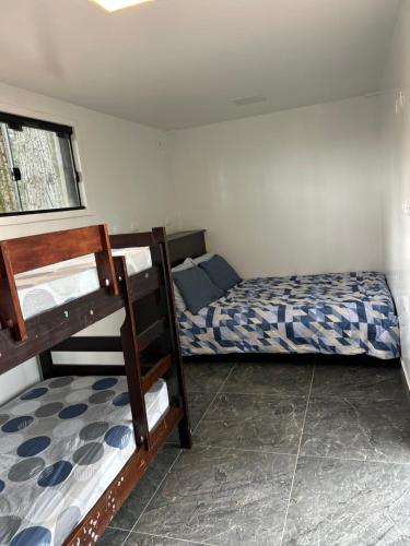 a bedroom with two bunk beds and a window at Chácara no bosque in São Bento do Sul