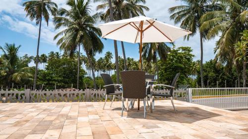 a table and chairs with an umbrella on a patio at Pousada Plenamar in Maragogi