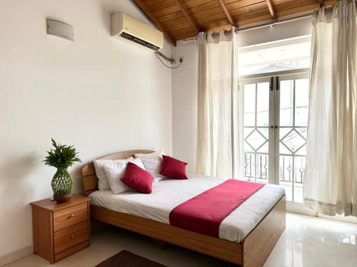 a bedroom with a bed with red pillows and a window at New Olive Villa in Negombo