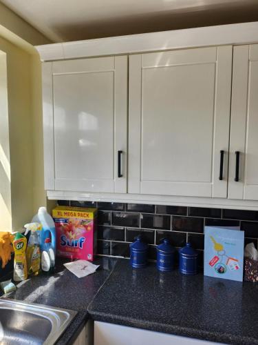 a kitchen counter with white cabinets and a sink at Spacious, 3 double bedroomed, free parking, 9 mins Elland Rd, nr Leeds City Centre in Leeds