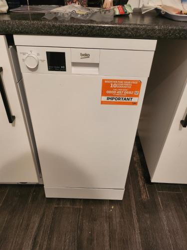a white dishwasher under a counter in a kitchen at Spacious, 3 double bedroomed, free parking, 9 mins Elland Rd, nr Leeds City Centre in Leeds